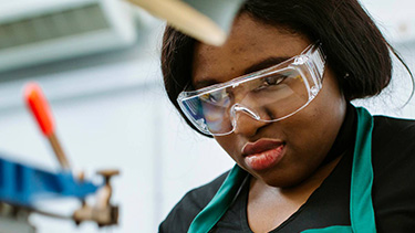 Female student studying in the classroom wearing safety goggles