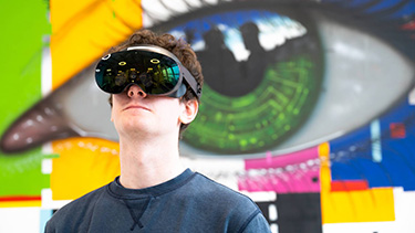 Student wearing virtual reality goggles in computer science class