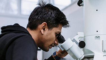 Male student looking through microscope