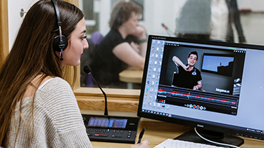 Female student with a headset watching a video on a desktop PC