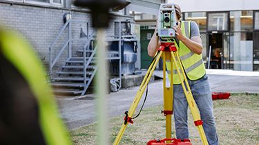 student looking through a total station placed on a tripod